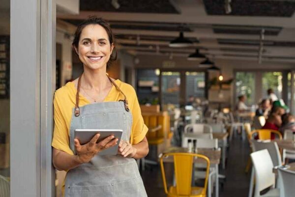 Dueña de un pequeño restaurante usando una tablet para gestionar su pyme.
