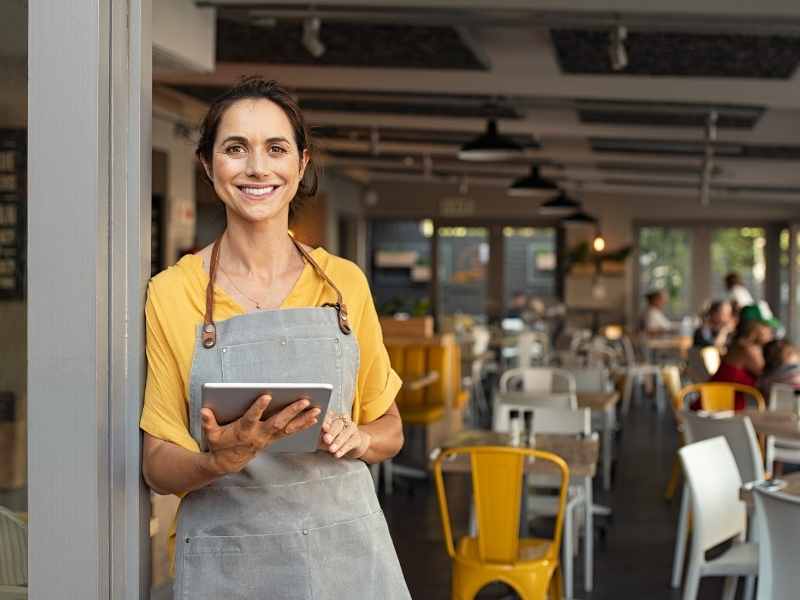 Dueña de un pequeño restaurante usando una tablet para gestionar su pyme.
