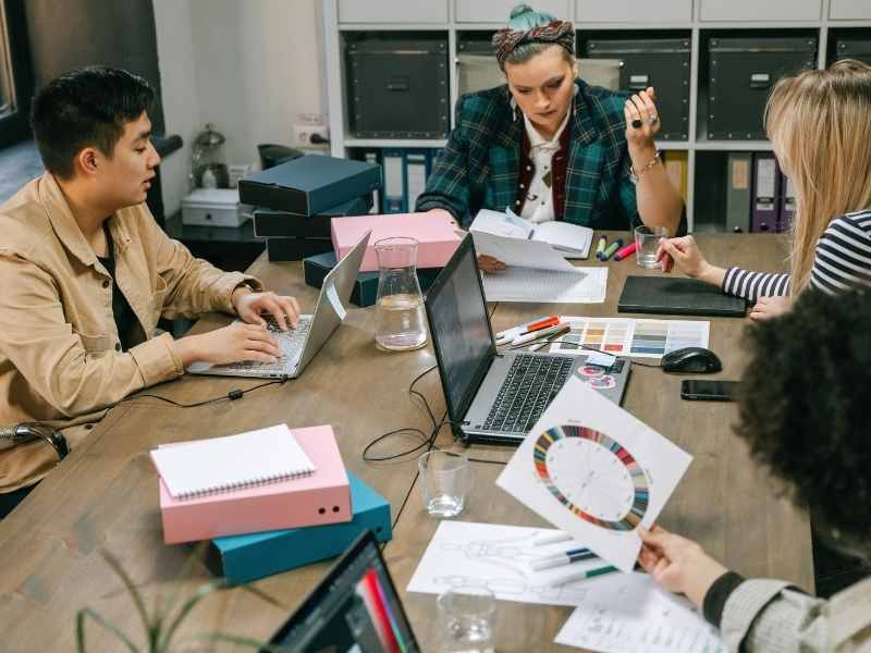 Equipo de una pequeña empresa reunido en mesa de trabajo revisando gráficos y estrategias.