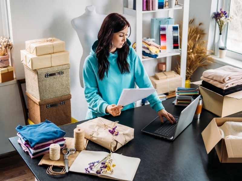 Emprendedora organizando productos y revisando pedidos en su taller para su tienda online.
