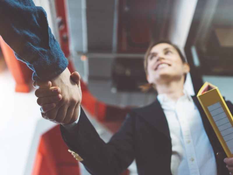 Apretón de manos entre representantes de una empresa grande y una pyme sellando una alianza comercial.