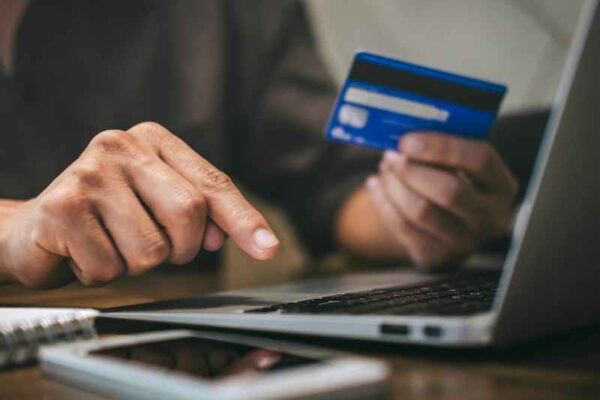 Persona pagando en laptop con tarjeta en mano, ilustrando la decisión de compra antes de inscribirse.